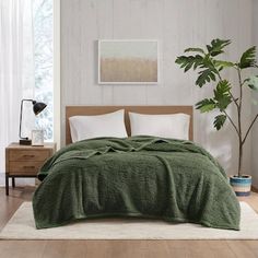 a bed in a room with a green comforter and two pillows on the floor