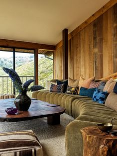 a living room filled with lots of furniture and a large window covered in wood paneling