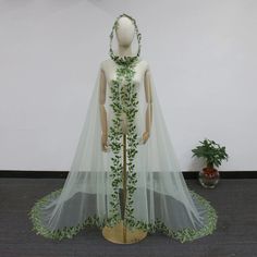 a mannequin wearing a white and green wedding dress with leaves on the skirt