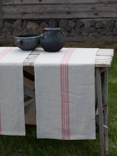 a table with two bowls on top of it next to a wooden bench in the grass