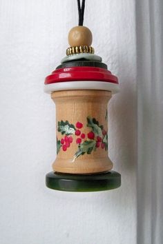 a wooden ornament hanging from a wall with holly and berries painted on it