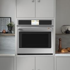 an oven built into the wall in a kitchen with gray cabinets and counter tops,