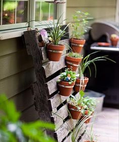 a wooden pallet filled with potted plants on the side of a home's porch