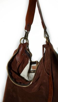 Handmade suede hobo bag make with soft cognac suede. The bag is closed with a zip. The bag has a strong cognac leather shoulder belt. This bag is unlined, inside there is a big cotton zipped pocket. Inside there is a leather string with a carabiner for your keys or phone case or for a purse. The leather strap is adjustable (22/44 inch) so you can wear the bag on your shoulder or crossbody. To add an extra touch to the bag you can buy the short handle which measures 18 inch in length and is avail Brown Suede Bag With Zipper Closure, Everyday Suede Shoulder Bag With Zipper Closure, Leather Brown Hobo Bag With Zipper Pocket, Brown Leather Hobo Bag With Zipper Pocket, Brown Leather Hobo Bag With Brass Hardware, Suede Hobo Bag With Zipper For Everyday Use, Everyday Leather Hobo Bag With Leather Trim, Everyday Suede Hobo Bag With Zipper Closure, Brown Hobo Bag With Brass Hardware For Travel