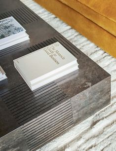 a coffee table with books on it and a couch in the back ground behind it