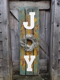 a wooden sign that says joy with a wreath on the front and side of it