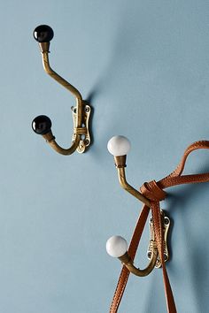 there are two hooks on the wall with leather straps attached to them and one hook has three balls in it