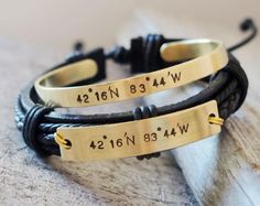 two personalized bracelets are shown on top of a piece of wood and leather