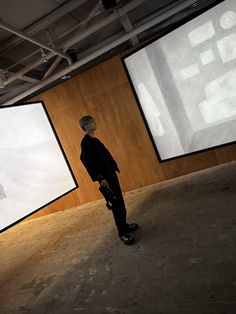 a man is standing in front of two large screens that are hanging on the wall