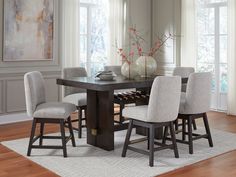 a dining room table with six chairs and a vase on the table in front of it