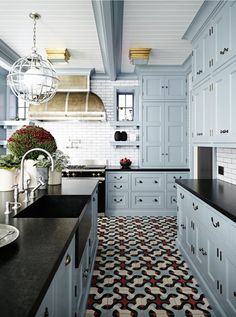 a kitchen with white cabinets and black counter tops, an area rug in the middle