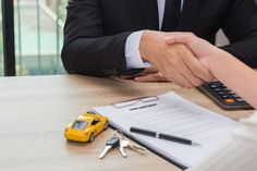 two people shaking hands at a table with keys and paperwork on it, next to a calculator