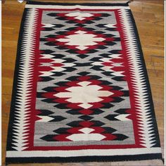 a red and black rug on the floor with wood floors in front of it,