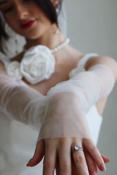 a woman in a wedding dress holding her hand out to the side with both hands