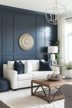 a living room with dark blue walls and white furniture in the corner, along with a coffee table