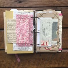 an open book with papers on it sitting on top of a wooden table next to a pair of scissors