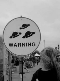 a woman standing next to a sign that says warning