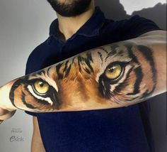 a man with a tiger face tattoo on his arm and hand, holding up the arm