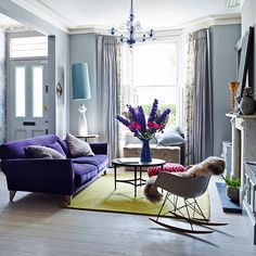 a living room filled with furniture and a chandelier hanging from the ceiling over a fire place