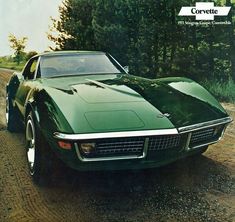 a green sports car parked on the side of a dirt road next to some trees