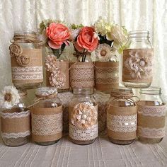 there are many jars that have flowers in them on the table and one is made out of burlap paper