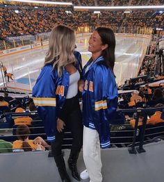 two women standing next to each other at a hockey game