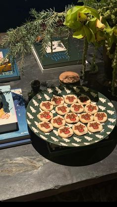 there is a plate with cookies on it next to books and a potted plant