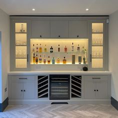 an empty bar with several bottles and glasses on the shelves in front of it is lit by recessed lights