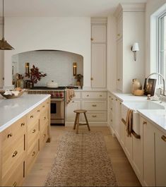 a kitchen with an oven, sink and counter tops in white painted cabinetry next to a large window