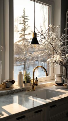 a kitchen sink sitting under a window next to a vase filled with flowers and candles