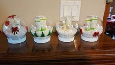 four snow globes with candles and bows on them are sitting on a wooden table