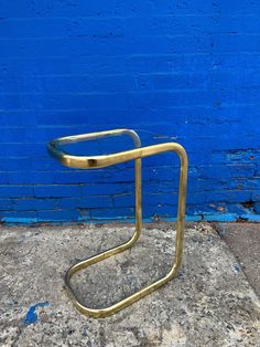 a gold metal chair sitting on top of a cement floor next to a blue wall