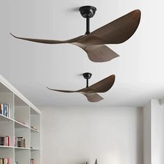 two ceiling fans are hanging from the ceiling in a room with white walls and bookshelves