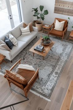 a living room with couches, chairs and rugs in front of large windows