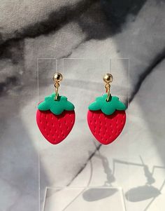 These strawberry earrings were made by hand using red and green polymer clay. They are perfect to wear during the summer or anytime of the year.  They are very lightweight and comfortable. Gold colored stainless steel ball posts. Lead and nickel free. Size - 1.25" Each piece is handmade and sanded. There may be small imperfections and no two are exactly alike. You may receive the earrings pictured or a similar pair. Trendy Red Resin Earrings, Green Resin Fun Earrings, Fun Red Resin Earrings, Playful Red Drop Earrings, Fun Style Red Resin Earrings, Fun Red Resin Jewelry, Red Drop Earrings In Polymer Clay, Playful Red Earrings For Pierced Ears, Playful Red Dangle Jewelry