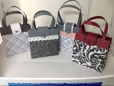 four bags are sitting on top of a table with ribbon tied around them and one bag is black, white, red, and gray