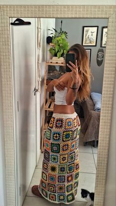 a woman taking a selfie while wearing a crochet skirt and tank top