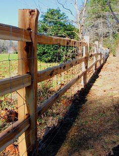 a wooden fence in front of a grassy field