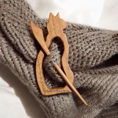 a wooden brooch sitting on top of a gray knitted sweater with an arrow in the middle