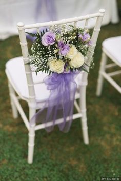 a bouquet of flowers sitting on top of a white chair next to a purple ribbon