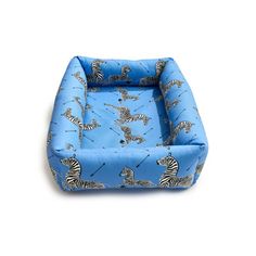 a small blue dog bed with zebras on it's sides and one in the middle