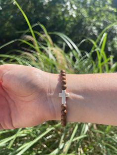 This wooden beaded bracelet features an off white stone cross in the center. This bracelet makes a beautiful gift for anyone! The cross means everything for us! Represent hope, love, faith, and salvation when you wear our gift our cross bracelets! Adjustable Cross Rosary Bracelet For Everyday, Adjustable Everyday Rosary Bracelet With Cross, Spiritual Cross Bracelets For Everyday, Elegant Cross Beaded Bracelets As Gift, Rosary Bracelet With 8mm Beads And Cross, Adjustable Cross Jewelry With Wooden Beads, Bohemian Cross Beaded Bracelets Adjustable, Adjustable Crucifix Jewelry With Wooden Beads, Adjustable Wooden Beads Cross Jewelry