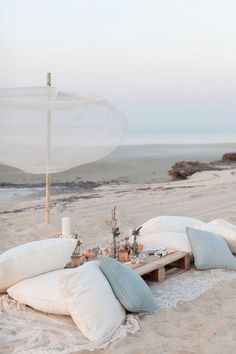 there is an umbrella and pillows on the beach