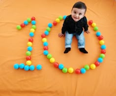 a young boy sitting on top of a bed made out of balls and plastic beads