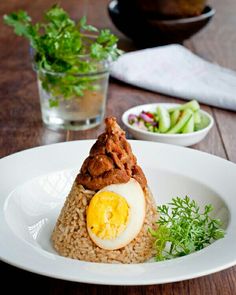 a white plate topped with rice and an egg on top of it next to a glass of water