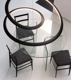 a glass table with chairs around it and a circular light fixture above the table on top