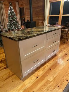 a kitchen island with granite counter tops in front of a window and christmas tree on the other side