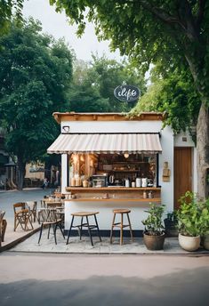 an outdoor cafe with tables and chairs under the shade of a tree in front of it