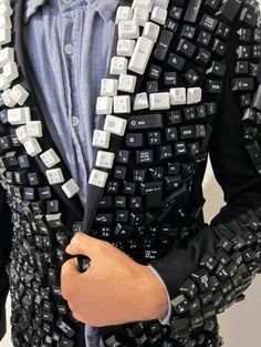 a man wearing a black and white suit with keyboard keys on it's lapel