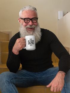 a man with a long white beard and glasses holding a coffee cup in his hand